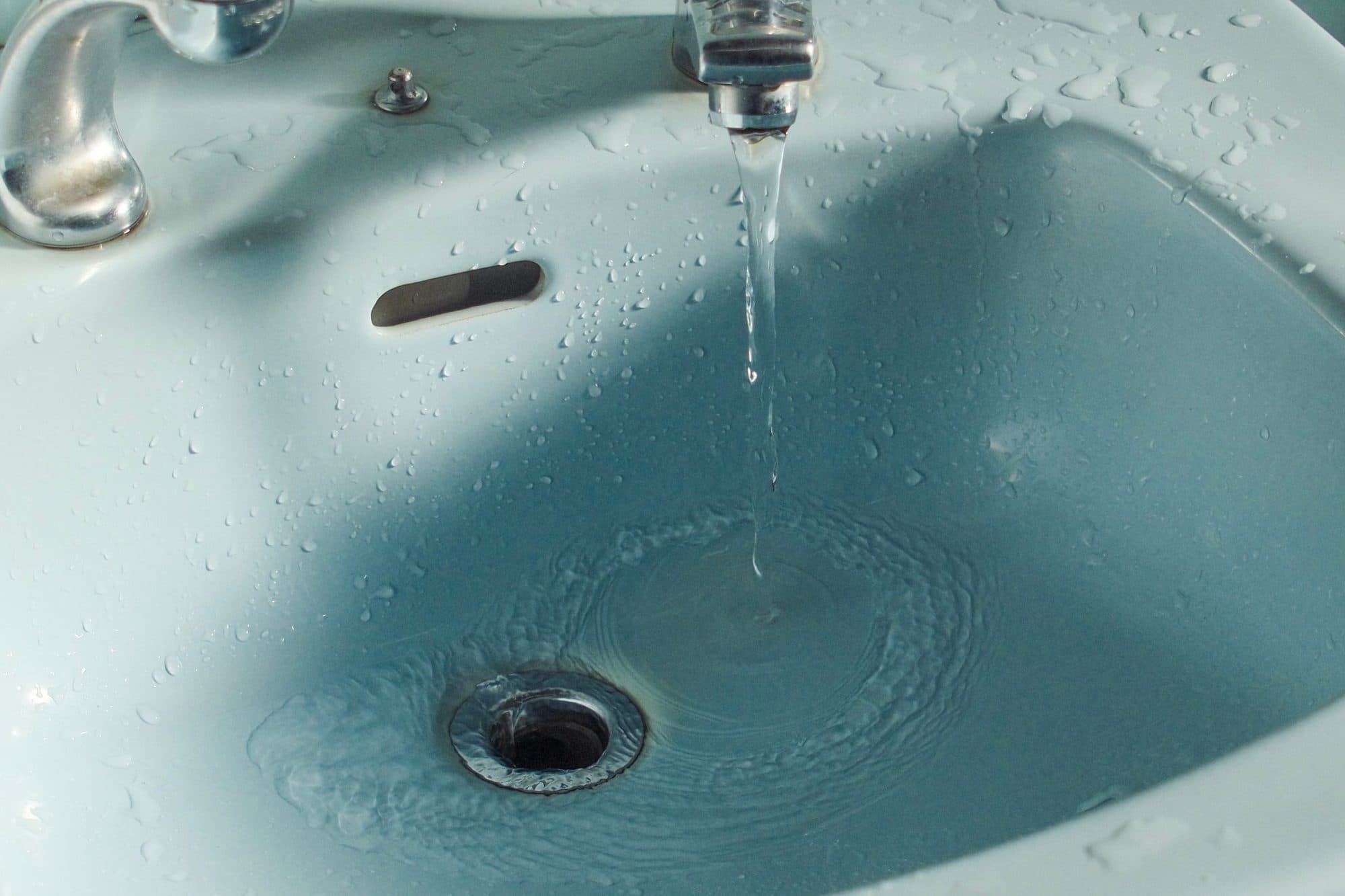 Water draining slowly from a bathroom basin plughole